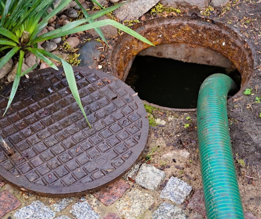 An opened septic access lid with the pump hose in place.